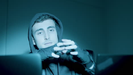 young caucasian man sitting at night in front of laptop screen and hacking