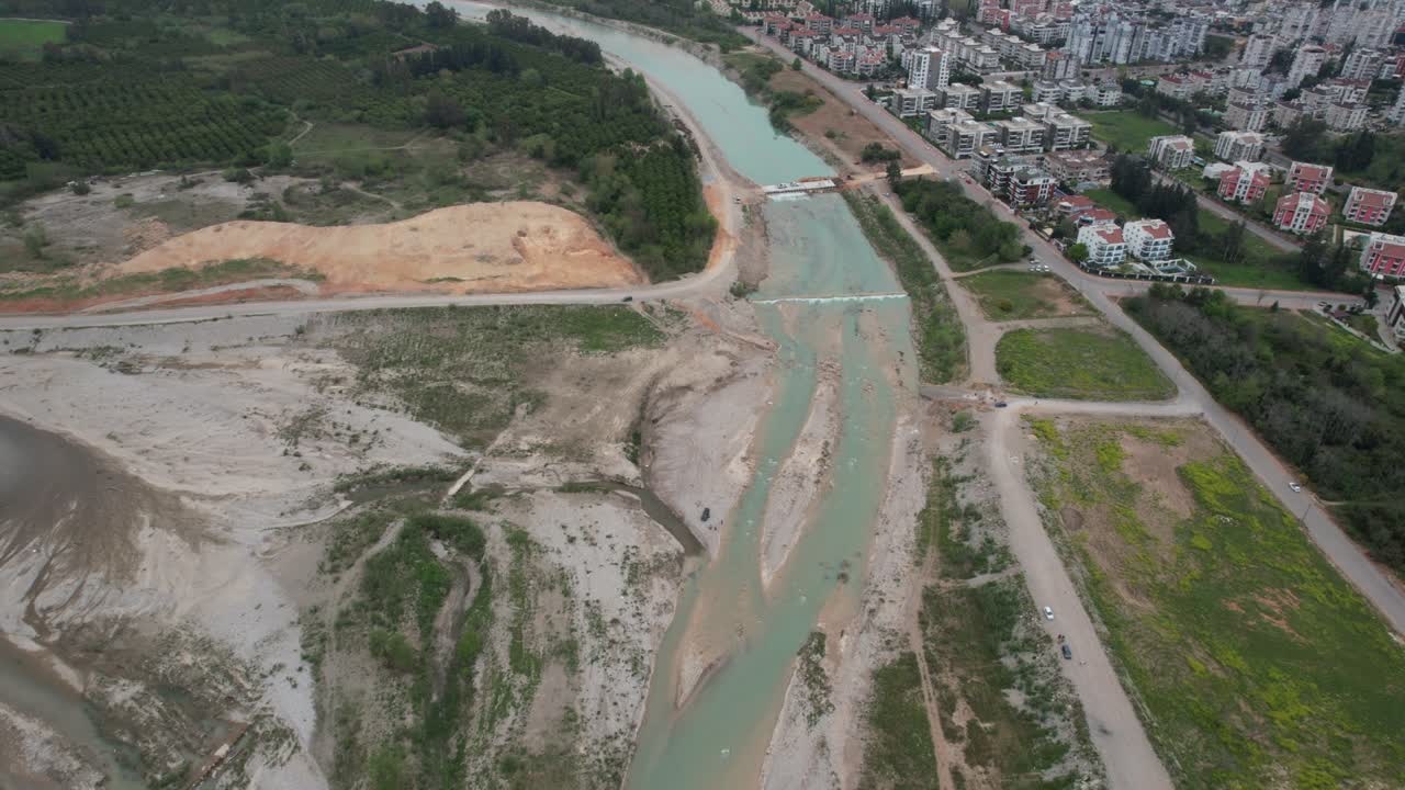 Video of nature and cityscape while flying over stream bed with drone.