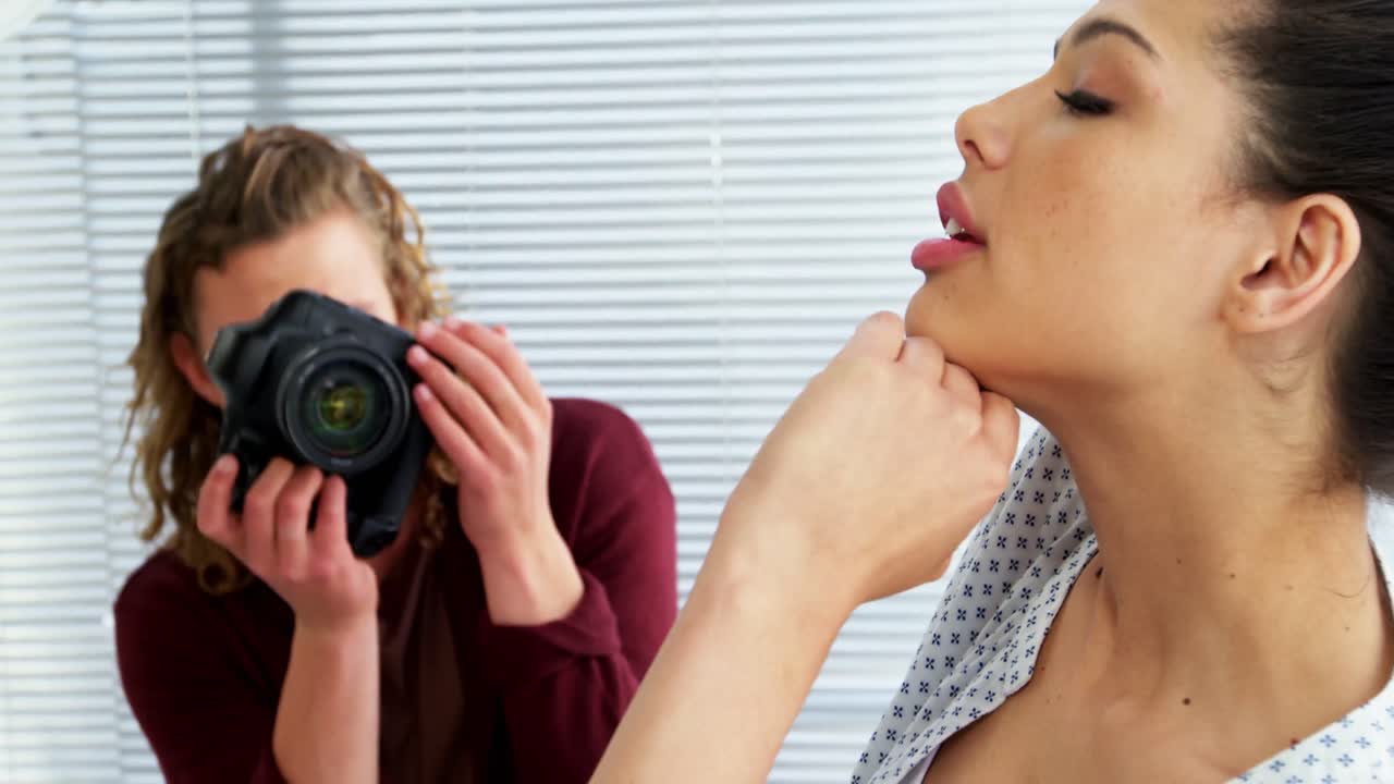 fotógrafo disparando con una modelo femenina durante una sesión de fotos de moda
