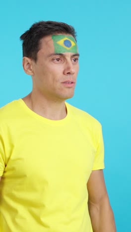 happy man with brazilian flag painted on face looking away