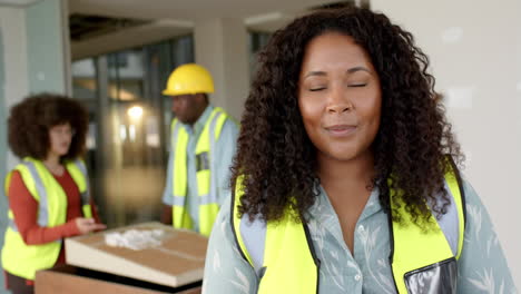 Smiling-casual-biracial-female-architect-with-tablet-in-office,-slow-motion,-copy-space