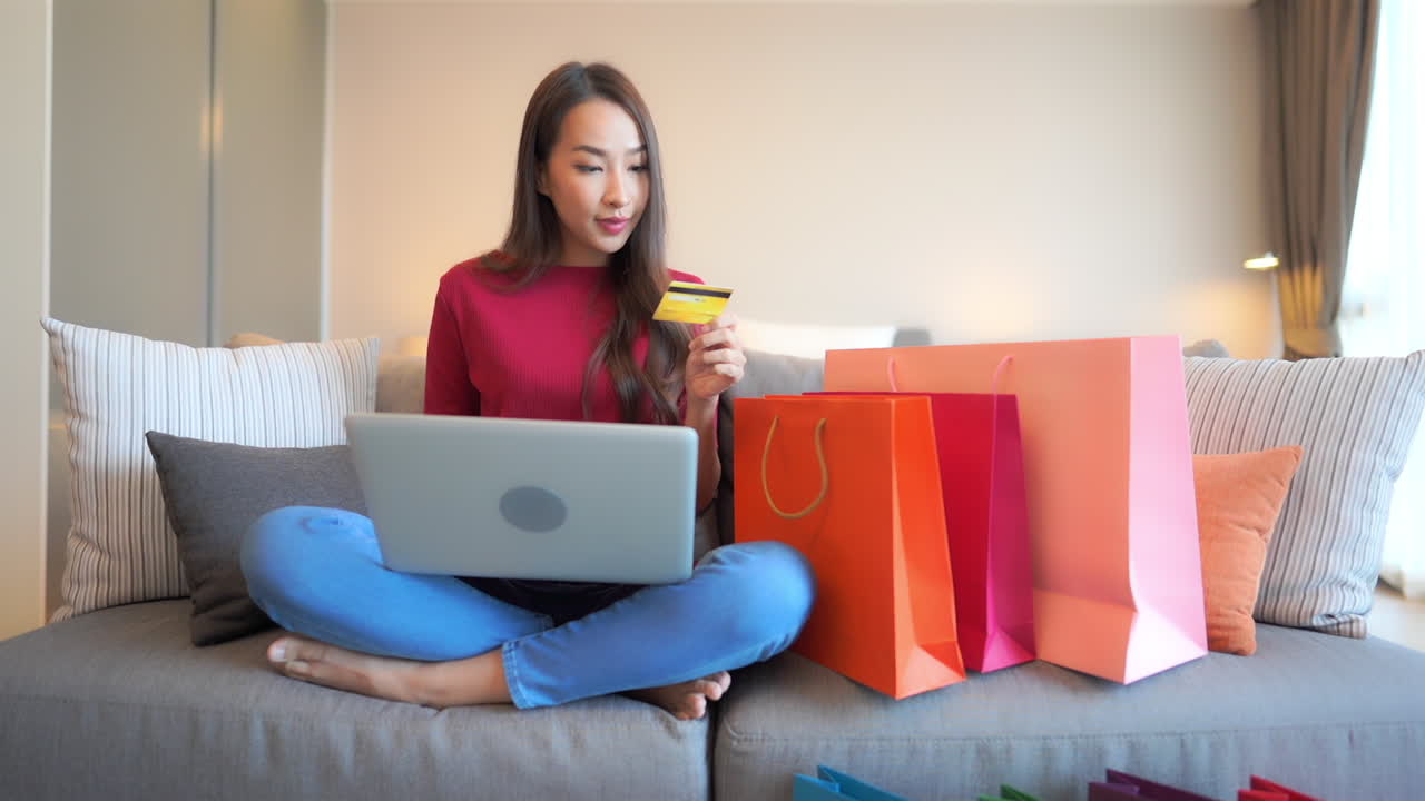 While shopping online, an attractive woman inputs her credit card and reacts in excitement when the sale goes through. copy space