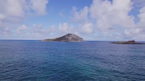 drone-footage-skimming-the-blue-water-pacific-Ocean-towards-an-island-near-Oahu-Hawaii-revealing-craters-in-the-volcanic-formation