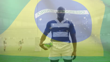 animation of brazilian flag waving over african american male rugby player holding a ball