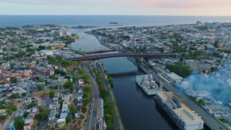 Aerial-forward-busy-city-Santo-Domingo,-establish-river-Ozama-and-sea-horizon