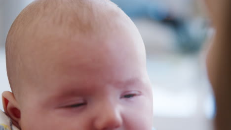 slow motion close up shot of mother sitting on sofa at home playing with baby son