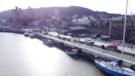 idyllic conwy castle and harbour fishing townscape boats on coastal waterfront aerial low angle reverse right