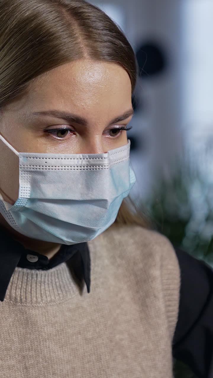 Pretty young lady in mask working with computer. Portrait quarantine employee in mask. Vertical video