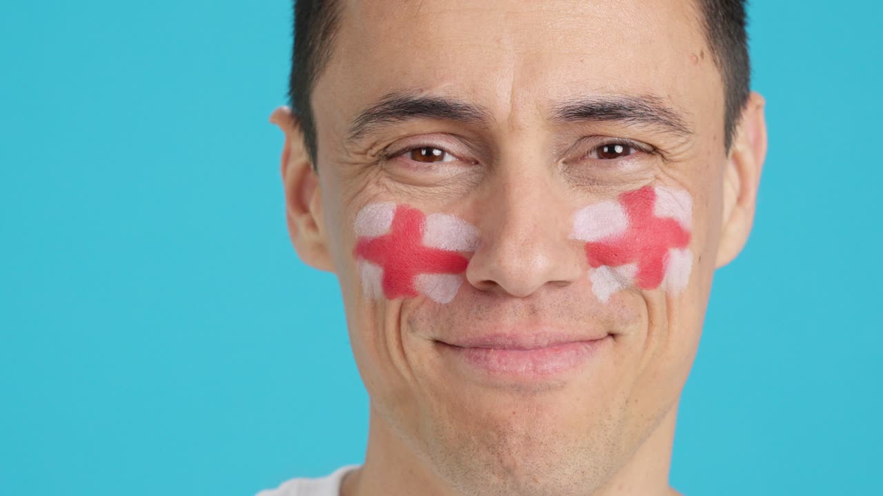 Uomo sorridente con una bandiera inglese dipinta sul viso
