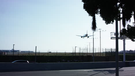 un avión se acerca a la pista del aeropuerto laxo al otro lado de la calle de una autopista con poco tráfico