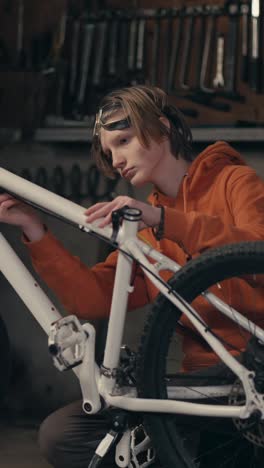 teenager repairing a white mountain bike in a garage