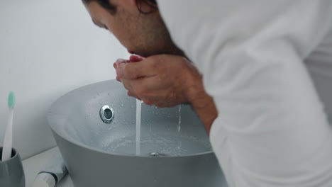 man washing hands in a bathroom sink
