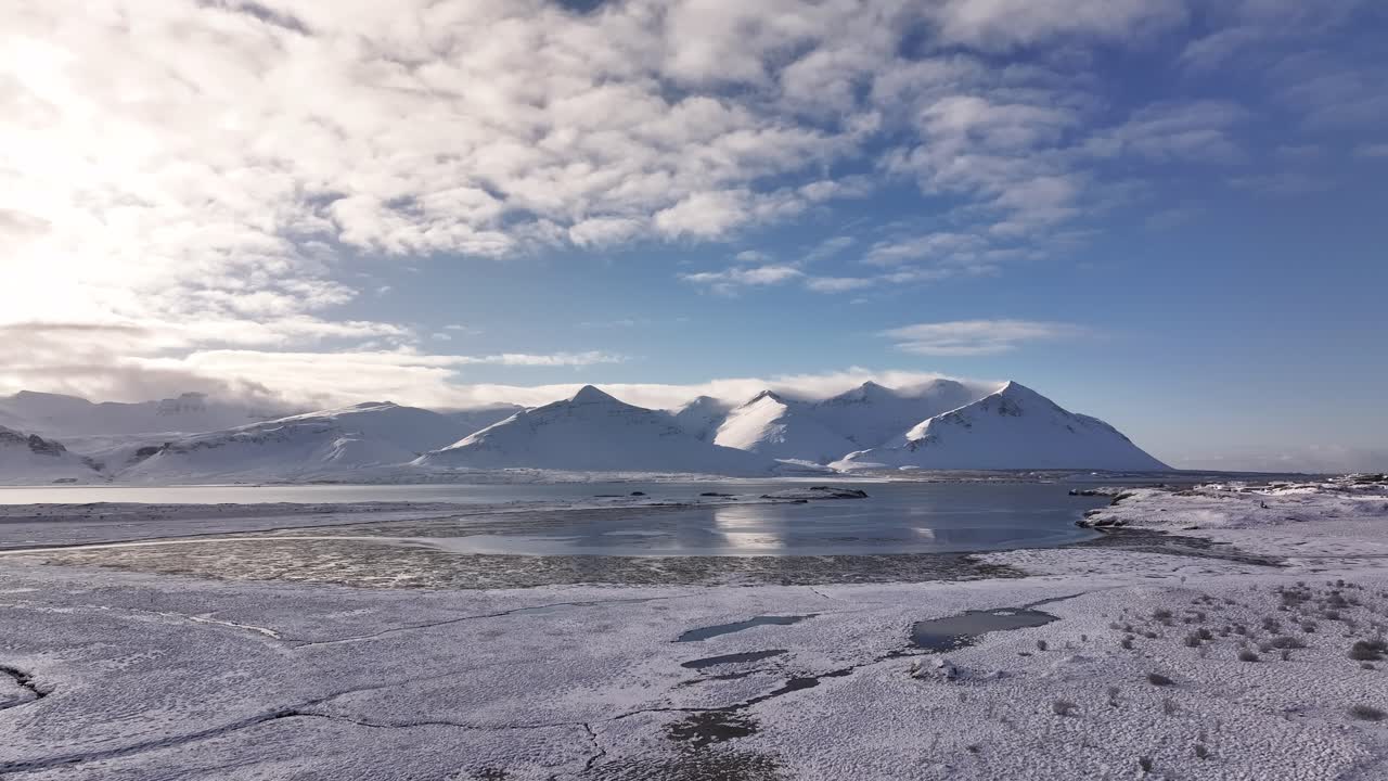 icy fjord mirrors snow capped Icelandic peaks near Borgarnes in bright sunlight