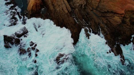 drone of light blue waves crash at bermagui blue pool rocks, australia