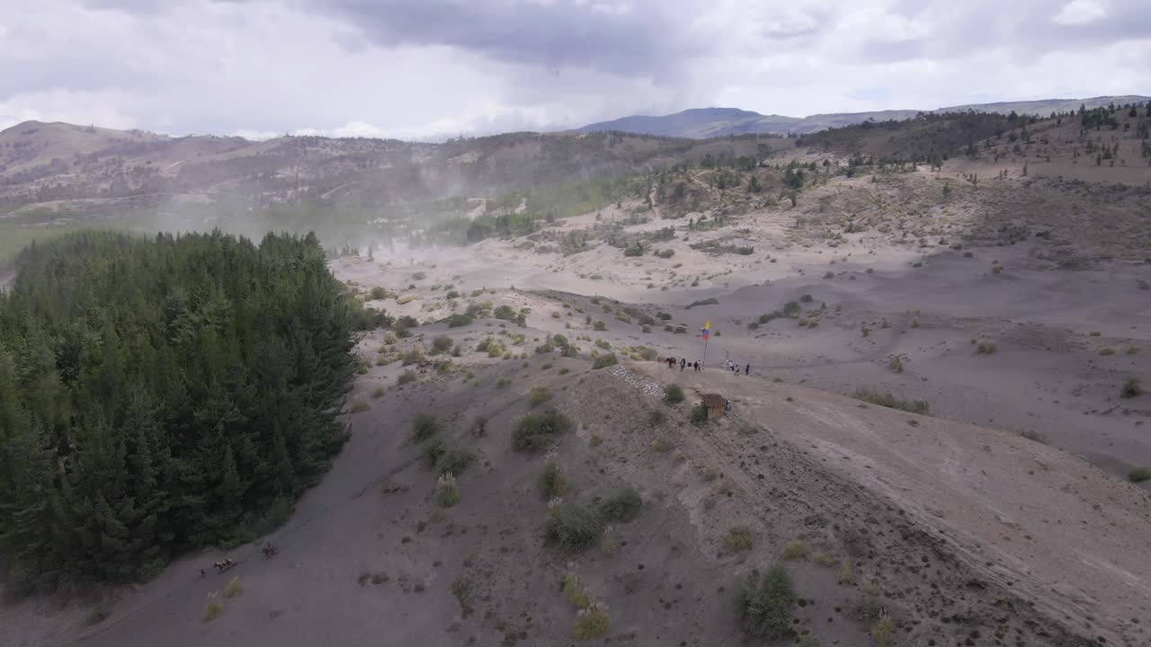 Group of people horseback riding on desert hill, orbit aerial view