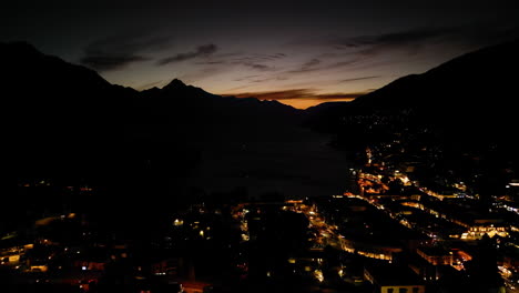dolly aéreo arriba de una ciudad iluminada por la noche al pie de una montaña