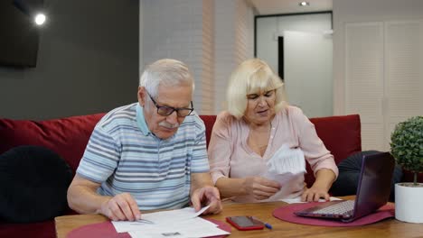 Senior-couple-checking-papers,-domestic-bills,-planning-budget-investment-loan-insurance-payment