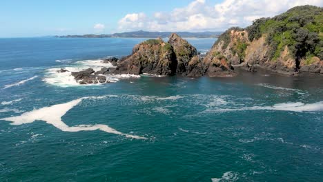 Aerial-drone-flying-backwards-over-a-rocky-shore,-following-a-seagull-bird