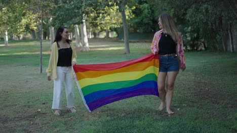 two women holding a pride flag in a park