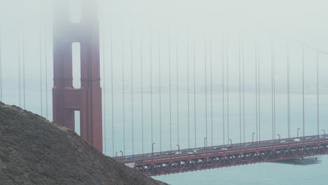 a medium shot of the golden gate bridge as traffic drives across in the foggy morning