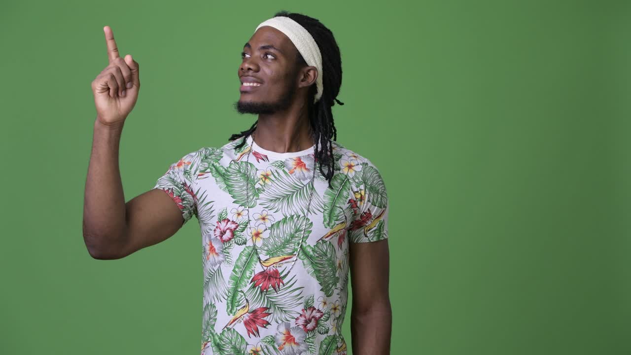 joven hombre africano guapo con dreadlocks contra un fondo verde