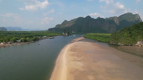 drone que revela un kayak en un banco de arena rodeado por un río y manglares en un día soleado en ao thalane krabi, tailandia, con montañas en la distancia