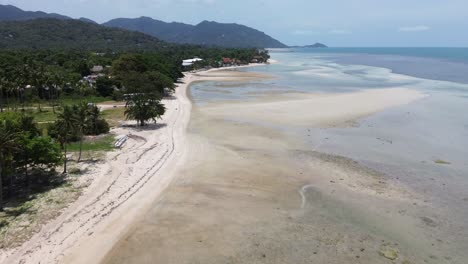 Aerial footage of Thong Sala Beach with a wide sandy shoreline, turquoise sea and lush tropical scenery on Koh Phangan island, Thailand