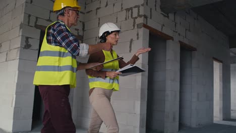 male and female caucasian engineers talking while walking up on stairs on the construction site.