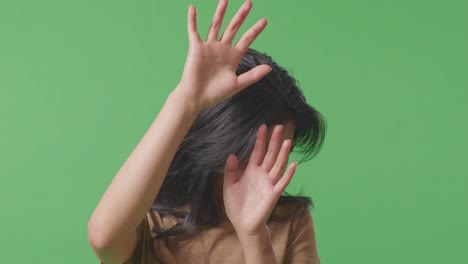 close up of young asian woman victim of violence with bruise on face making defending gesture by hands and fearing on green screen studio