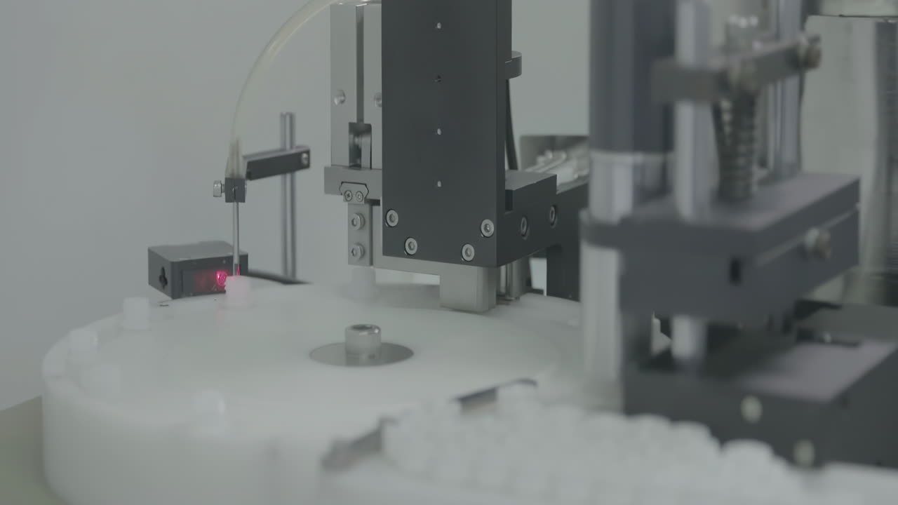 Medical worker control vaccine capping process in automated pharmaceutical production line manufacturing, cap placing on vials of vaccine injections drugs in a sterile factory environment setting