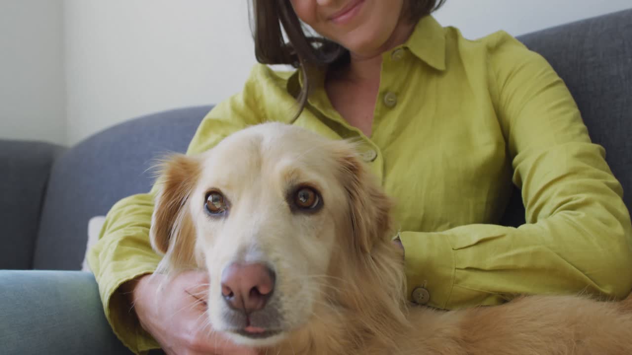 mujer caucásica sonriendo y sentada en el sofá con el perro
