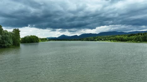 Drone-Aéreo-Cámara-Lenta-Vuela-Cerca-Del-Lago-En-El-Horizonte-Tormentoso-Paisaje-Eslovenia-Žovnek-Destino-De-Viaje-De-Europa-Del-Este