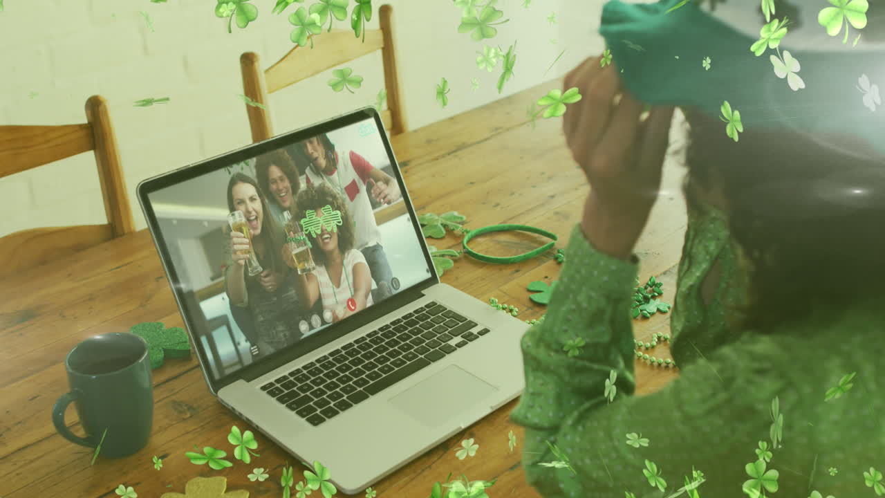 animación de hojas de trébol sobre una mujer celebrando el día de san patricio con amigos en una llamada de video portátil