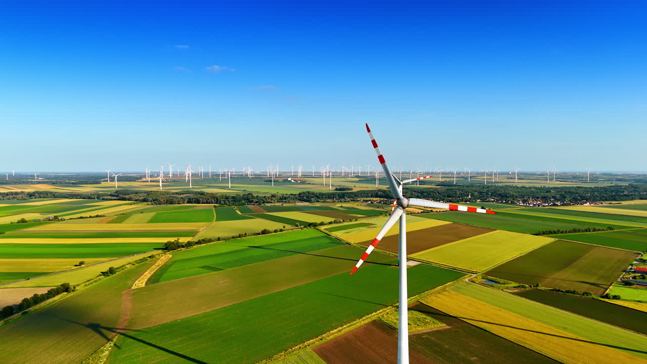 Approaching rotating blades of the windmill. Aerial perspective on the windfarms producing green energy.
