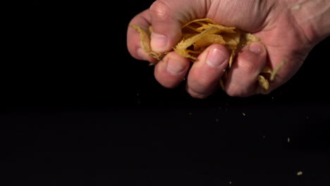 manos aplastando patatas fritas sobre un fondo negro