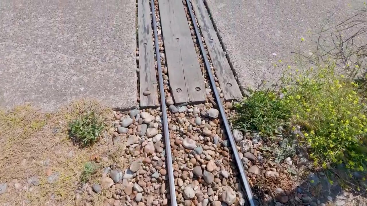 Camera moves forward along narrow winch rail tracks used to haul fishing boats up the shingle beach at the Stade in Hastings, England.
