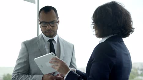 focused colleagues looking at tablet and talking