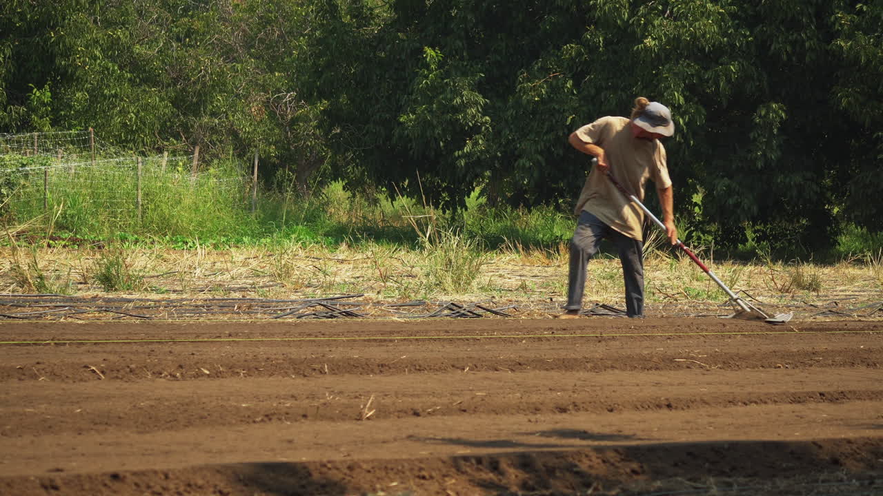 agricultor redneck usando un rastrillo para arar el campo, estilo de vida cotidiano del compatriota, tiro de movimiento lateral