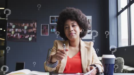 Animation-of-question-mark-symbol-over-biracial-businesswoman-with-afro-hair-writing-in-book