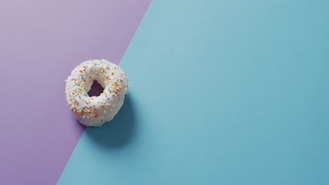 Video-Von-Donut-Mit-Zuckerguss-Auf-Violettem-Und-Blauem-Hintergrund