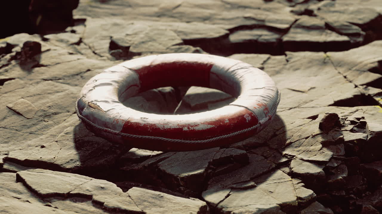 Lifebuoy rests on rugged rocks near water at golden hour
