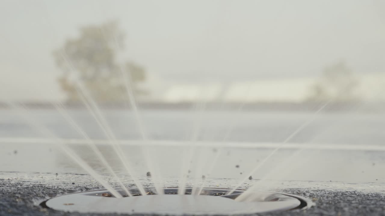 비 시 ⁇ 레이션 시스템의 클로즈업은 새로운  ⁇ 색 자동차가 지나간 도로에 물을 뿌립니다.