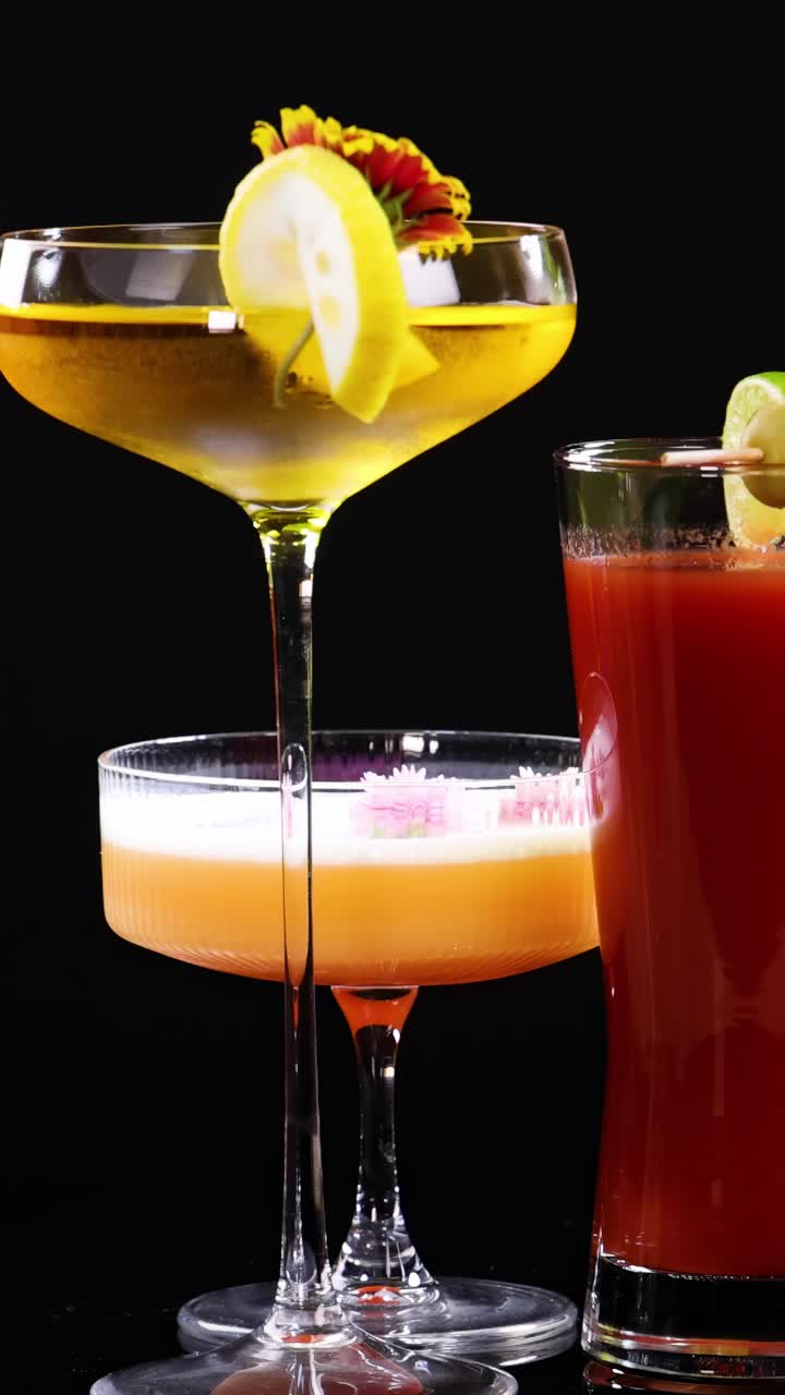 A variety of colorful cocktails with garnishes displayed against a black background, highlighting vibrant colors and elegant glassware