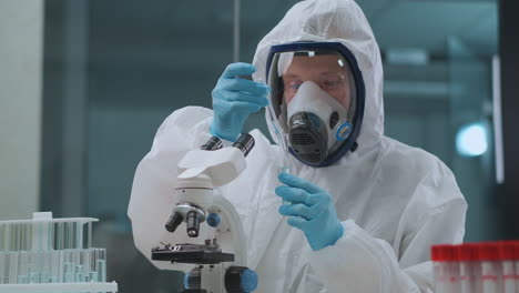 virologist is researching danger virus in laboratory man is dressed protective overall and face mask with respirator developing of bacteriological weapon