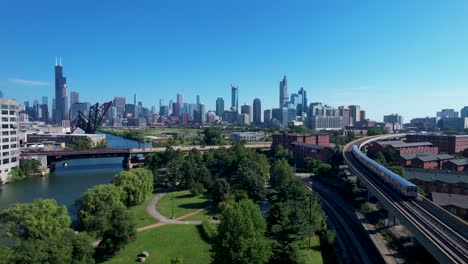 elevated train passes over city park chicago downtown skyline