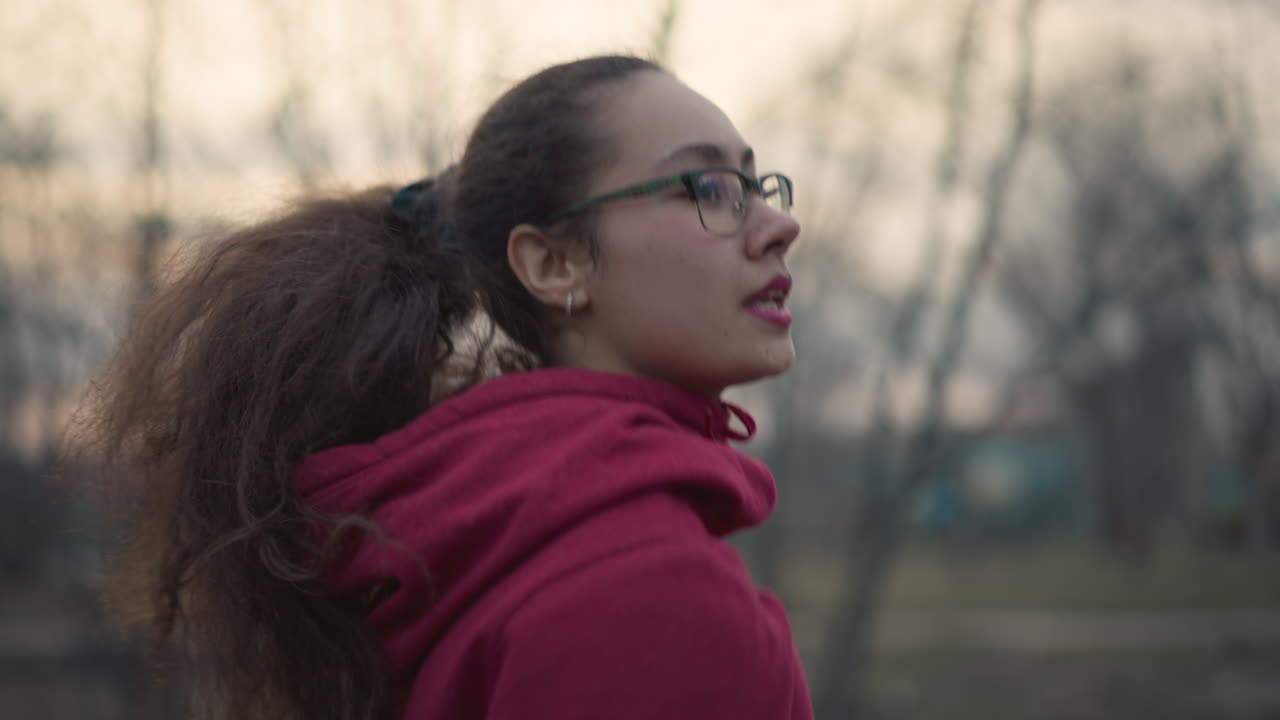 Una mujer concentrada corre rápido al atardecer; una corredora decidida acelera con el viento al caer la tarde; una mujer atlética corre con concentración y velocidad mientras la luz del día se desvanece en el crepúsculo.