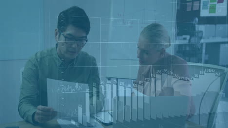 Analyzing financial graphs, business professionals collaborating in office setting