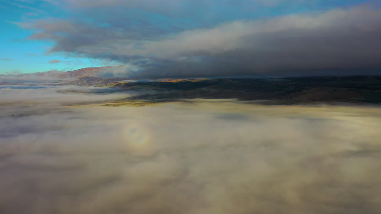 vista aérea de un dron volando sobre nubes de niebla que cubren un paisaje pintoresco