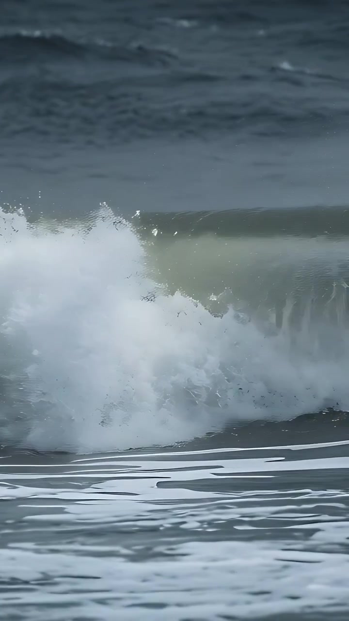 Vertical video: Swell approaching shoreline, breaking wave collapsing and releasing power into foam