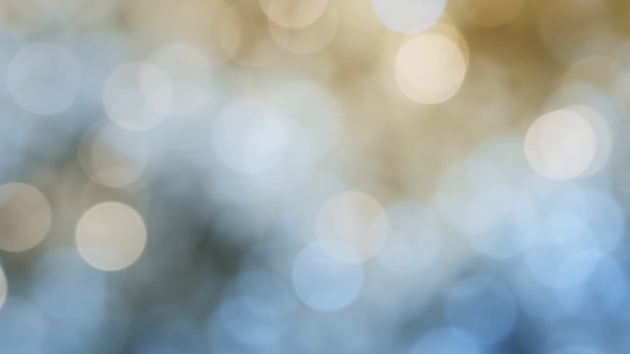 Bløde gyldenblå bokeh-lys gløder, drømmende ude af fokus baggrund med skinnende cirkulære højdepunkter, varm